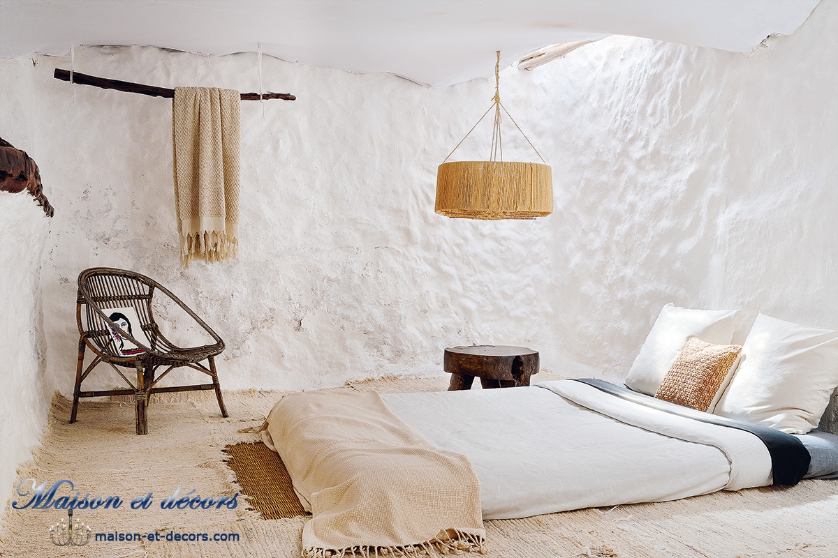 Une chambre toute blanche, avec des murs en terre chaulée et un éclairage par une lucarne en hauteur.