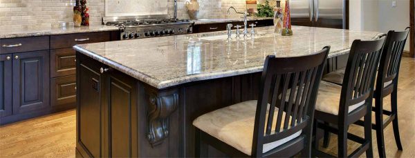 Un ilot central en bois sombre recouvert d'un plan de travail en pierre grise polie