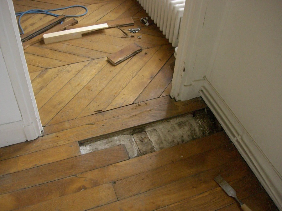 Le coin d'un parquet est enlevé pour être remplacé par des lames neuves