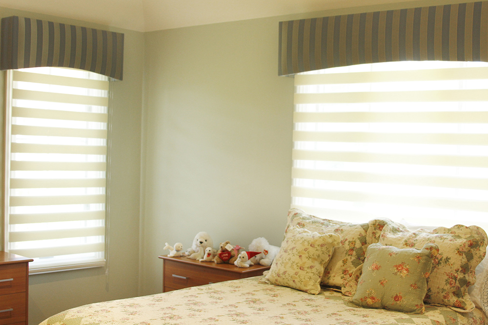 Lit encadré par deux fenêtres habillées de stores alternant les bandes opaques et les bandes transparentes