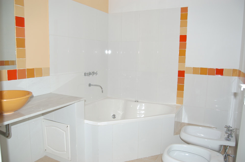 Salle de bains avec baignoire d'angle, lavabo et deux bidets